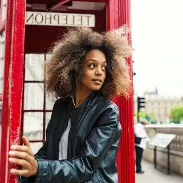 Woman stepping out of red telephone box